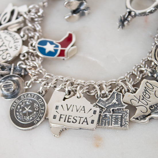 Silver charm bracelet with various charms on a white background