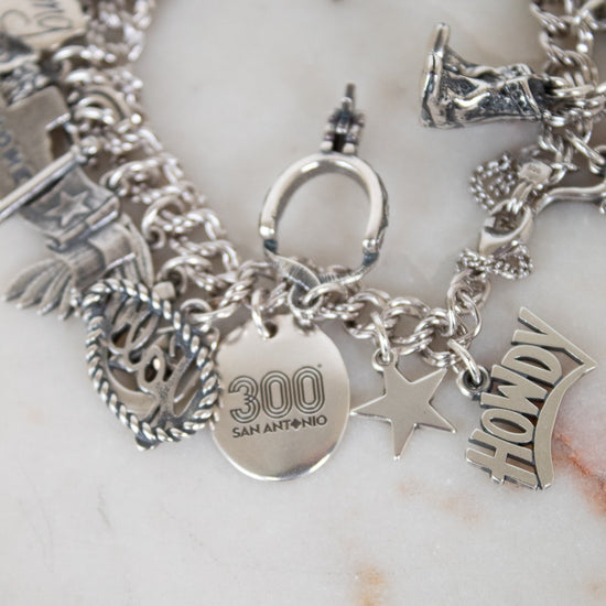 Silver charm bracelet with various charms on a white surface