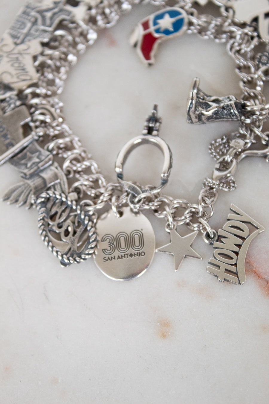 Silver charm bracelet with various charms on a white surface