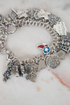 Silver charm bracelet with various charms on a marble surface