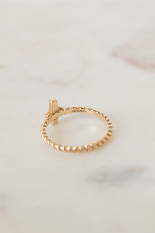Gold ring with a small cross on a marble surface