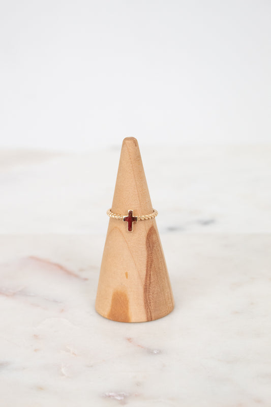 Wooden cone with a gold ring featuring a cross on a marble surface