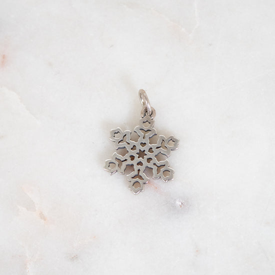Silver snowflake pendant on a white marble background