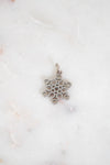 Silver snowflake pendant on a white marble background