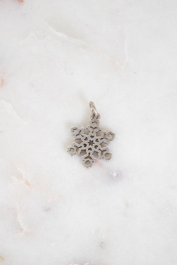 Silver snowflake pendant on a white marble background