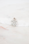 Silver snowflake charm on a white marble surface