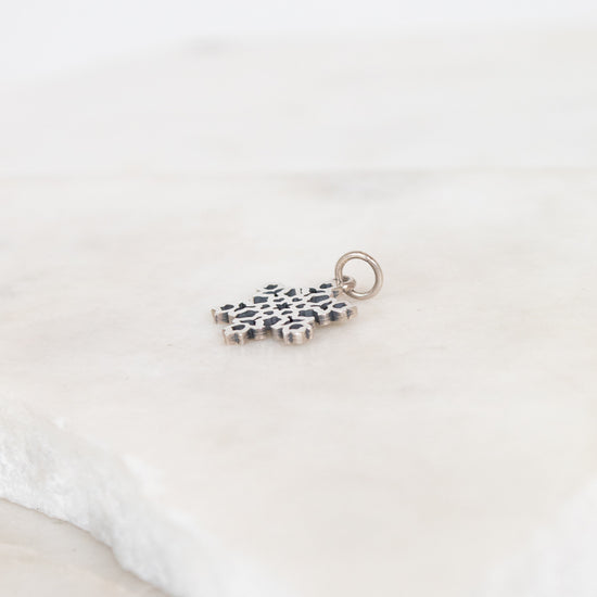 Silver charm with a snowflake design on a white background