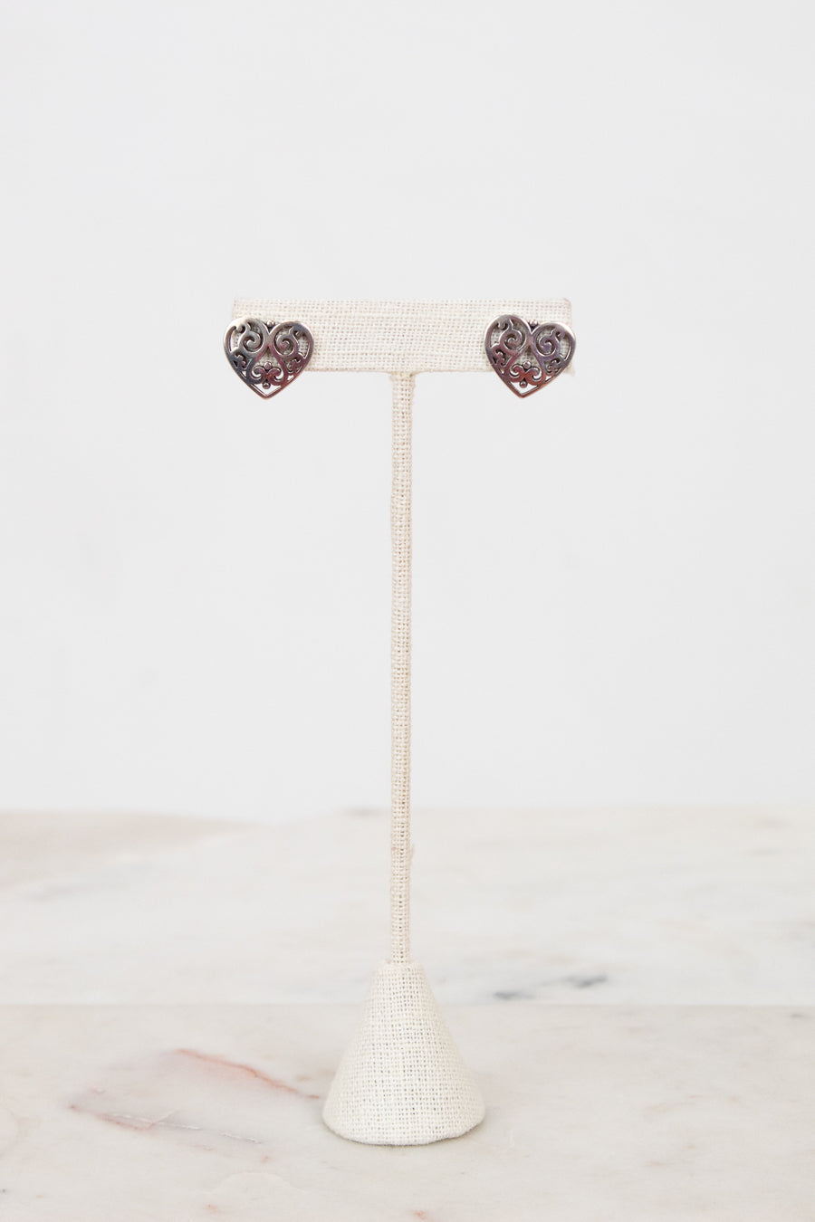 Heart-shaped earrings on a white stand with a white background