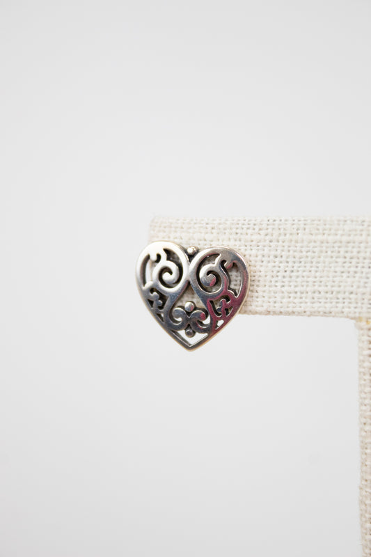 Heart-shaped metal close-up of earring with intricate heart design on a white background