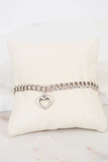 Silver bracelet with a heart charm on a white cushion