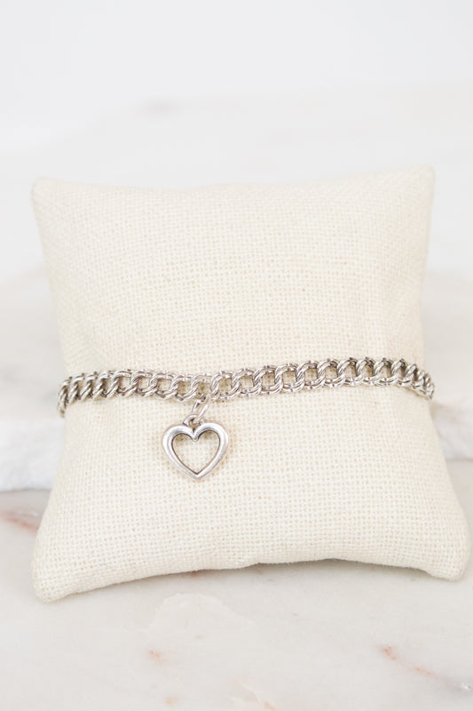Silver bracelet with a heart charm on a white cushion