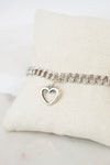Silver bracelet with a heart charm on a white cushion