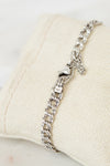 Silver chain bracelet on a beige cushion with a white background