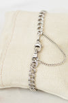 Silver chain bracelet on a beige pillow
