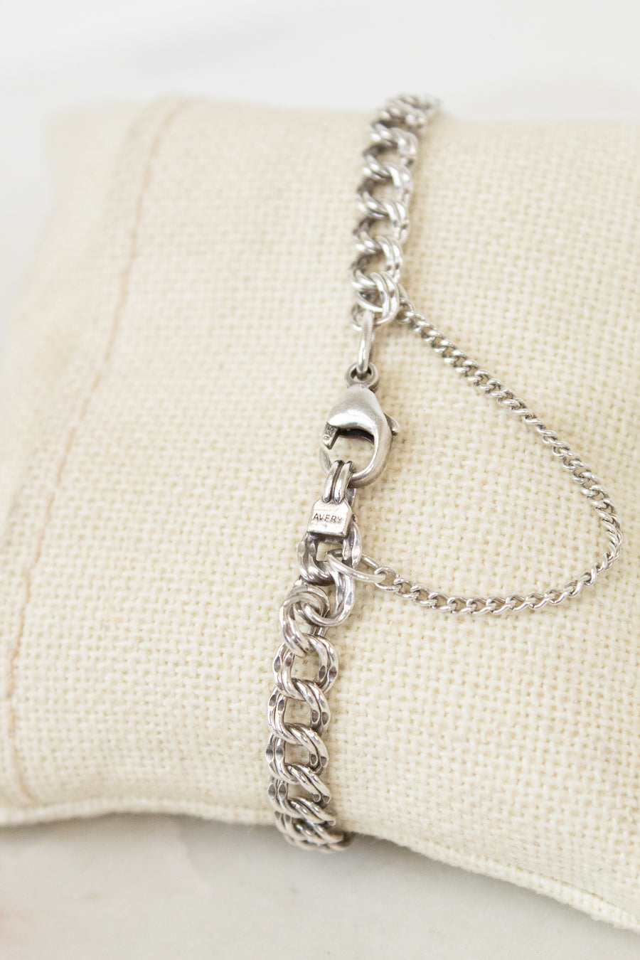 Silver chain bracelet on a beige pillow