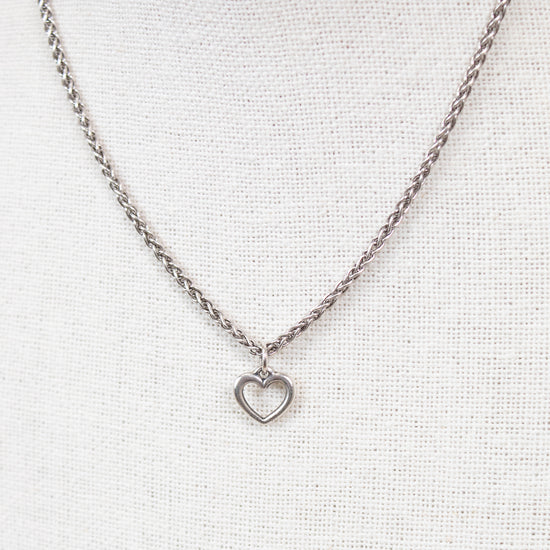 Silver necklace with a heart pendant on a light gray background