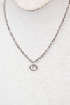 Silver necklace with a heart pendant on a light gray background