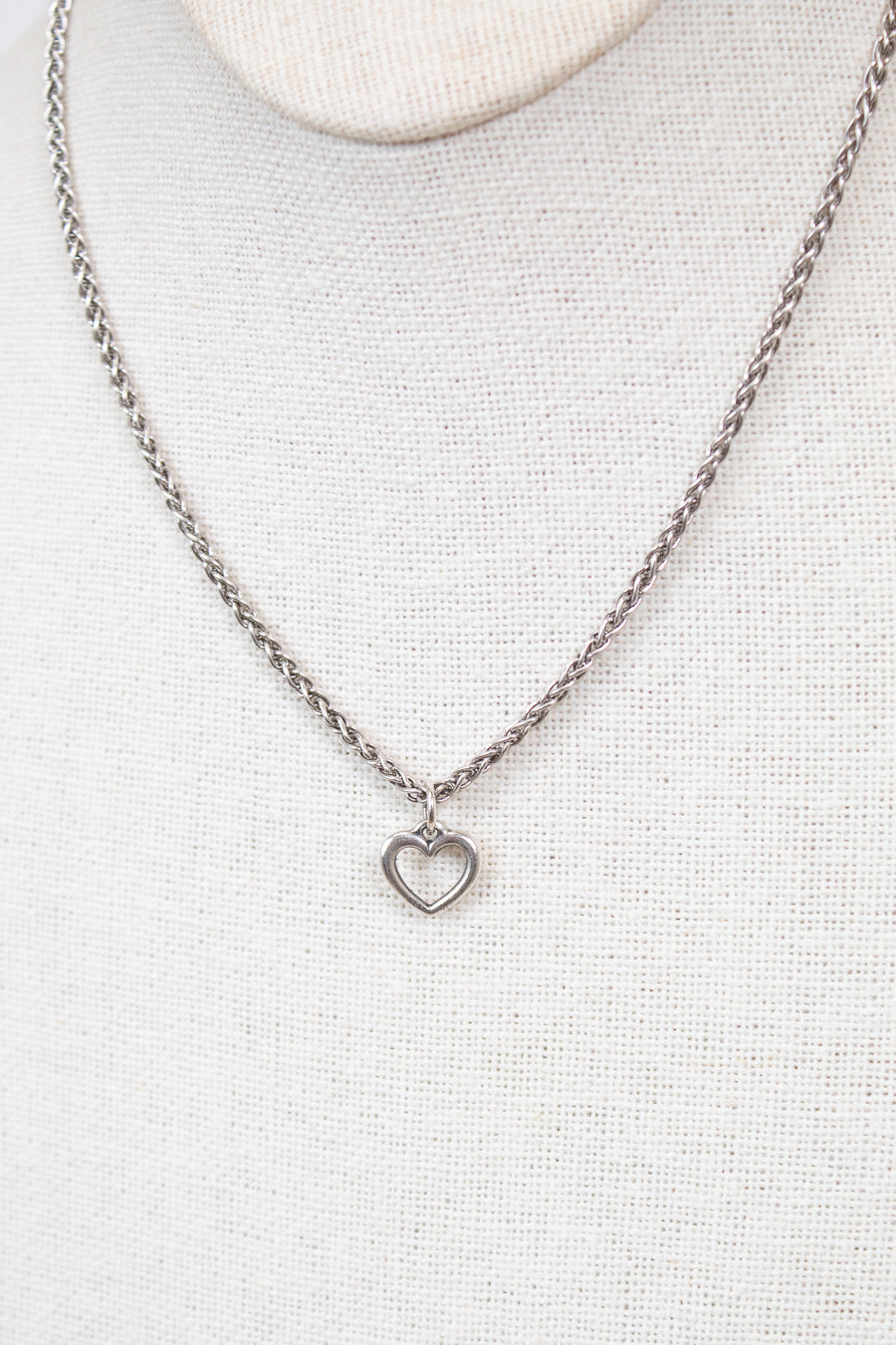 Silver necklace with a heart pendant on a light gray background