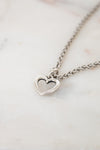 Silver heart-shaped pendant necklace on a marble surface