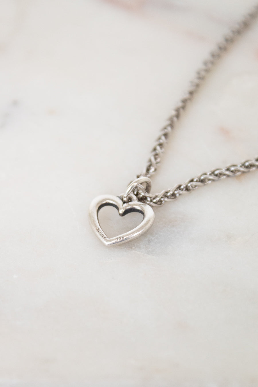 Silver heart-shaped pendant necklace on a marble surface