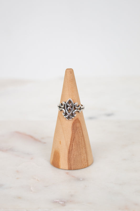Silver ring on a wooden cone against a light background