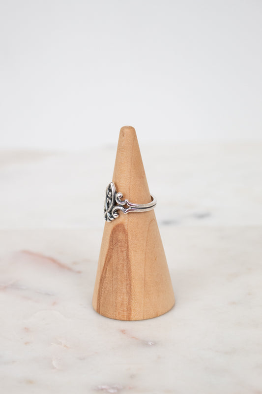 Silver ring on a wooden cone against a white background
