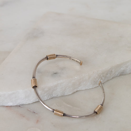 Bracelet with gold and silver wire design on a marble surface