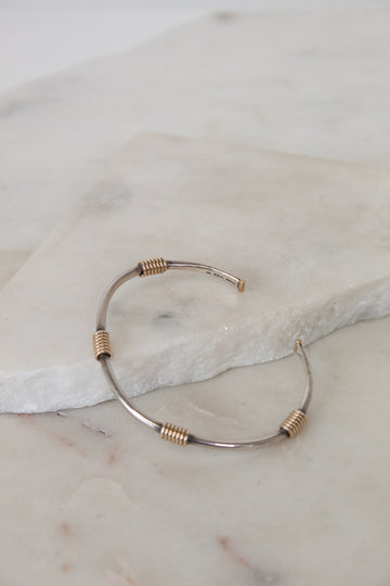 Bracelet with gold and silver wire design on a marble surface