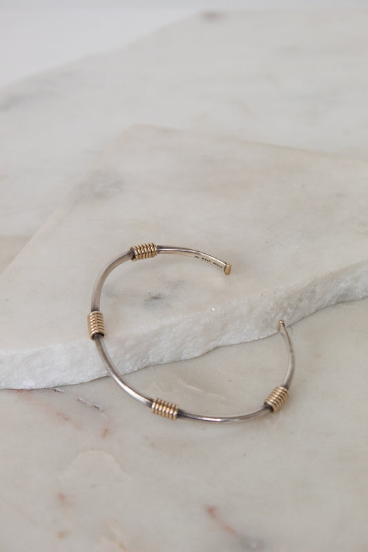 Bracelet with gold and silver wire design on a marble surface