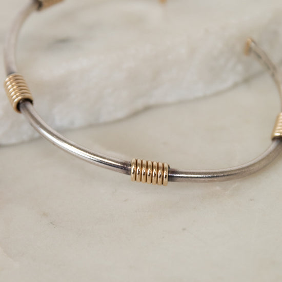 Silver and gold bracelet on a marble surface