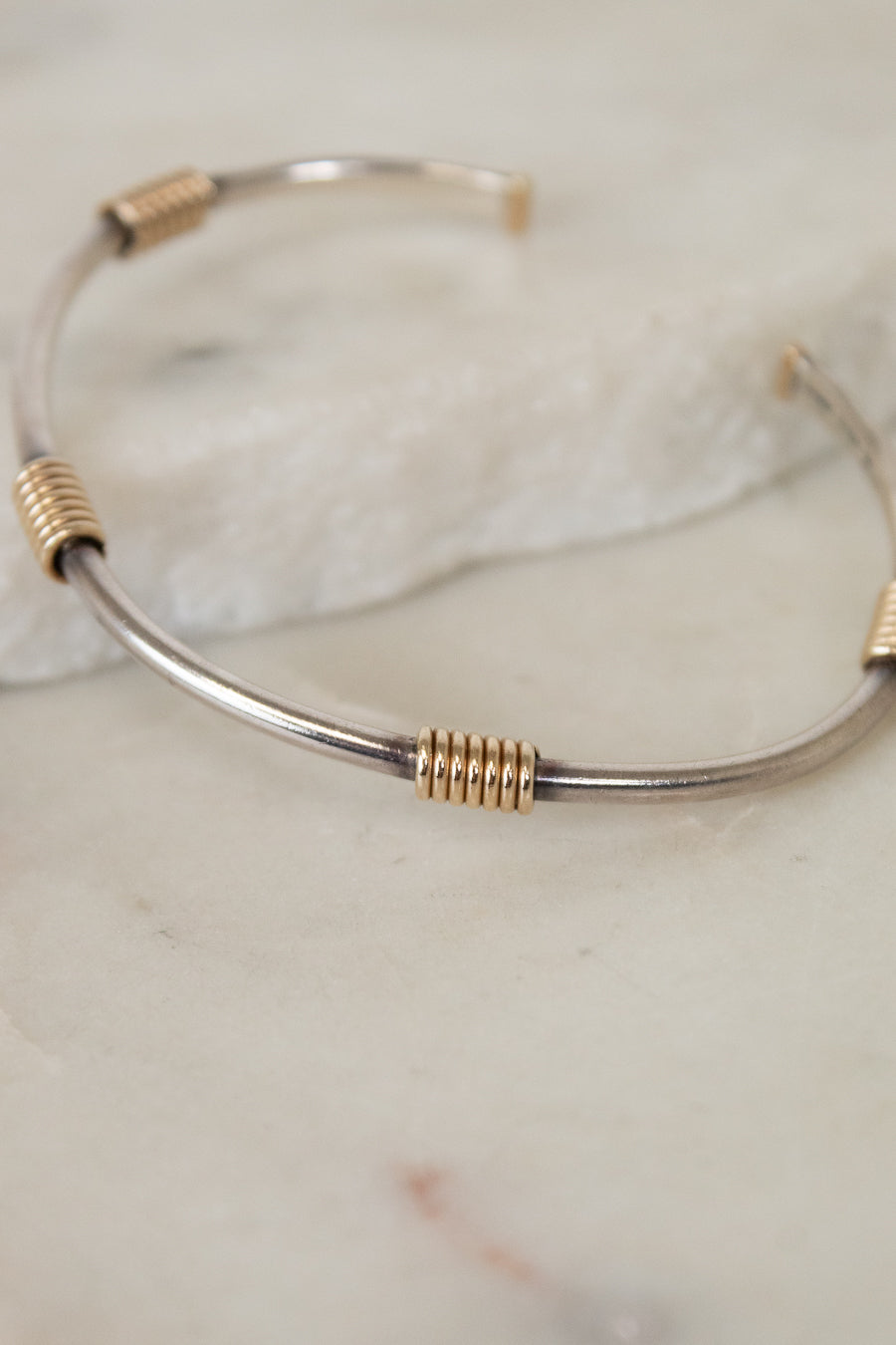 Silver and gold bracelet on a marble surface