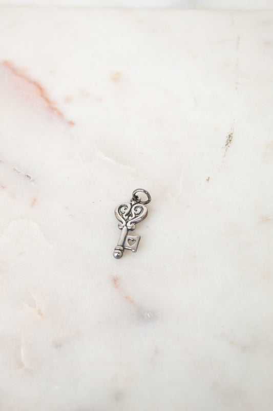 Silver key-shaped charm on a marble surface