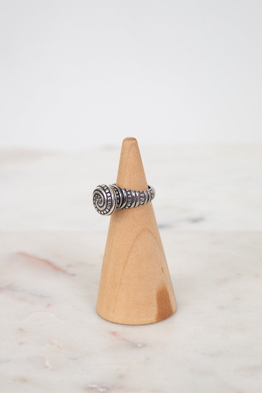 Silver ring on a wooden cone against a white background