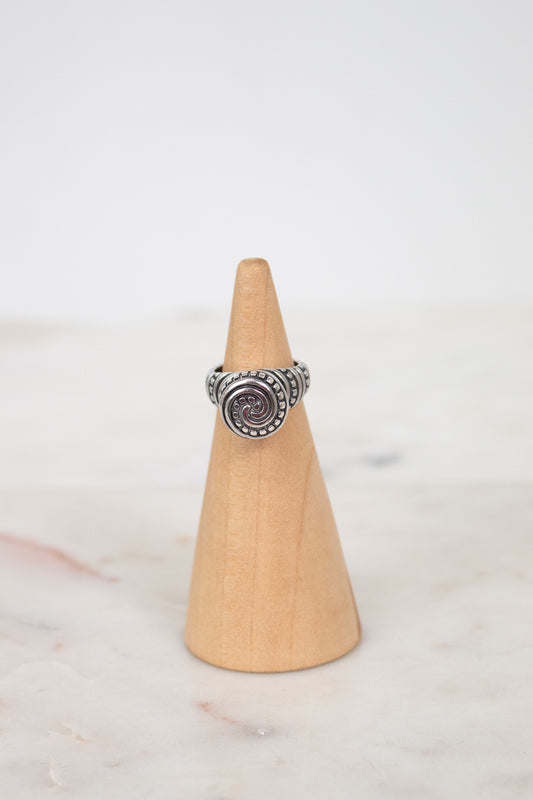 Silver ring on a wooden cone against a white background