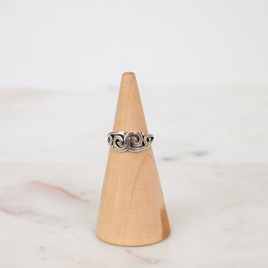Silver ring on a wooden cone against a marble background