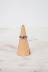 Silver ring on a wooden cone against a marble background