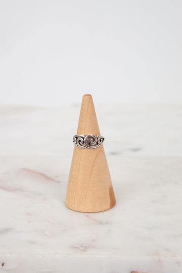 Silver ring on a wooden cone against a marble background