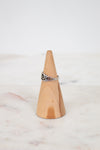 Silver ring on a wooden cone against a white background