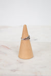 Silver ring on a wooden cone against a white background