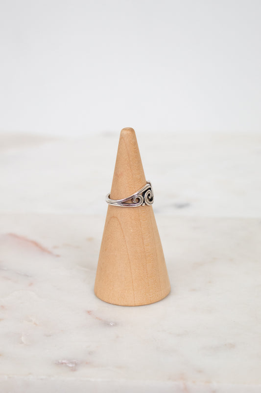 Silver ring on a wooden cone against a white background