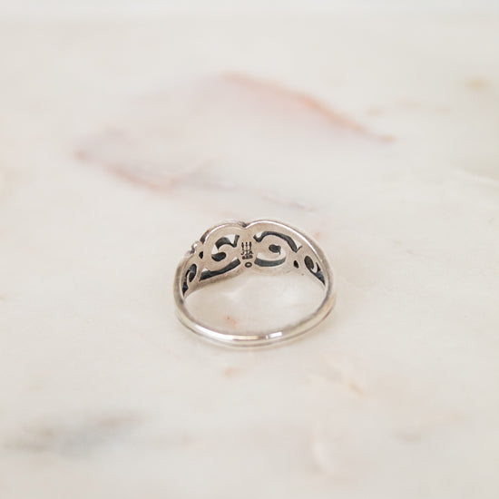 Back inside of silver ring with intricate design on a marble surface