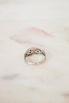 Back inside of silver ring with intricate design on a marble surface