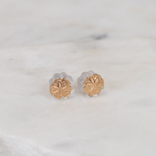 Gold stud earrings on a marble surface