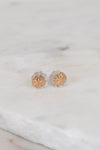 Gold stud earrings on a marble surface