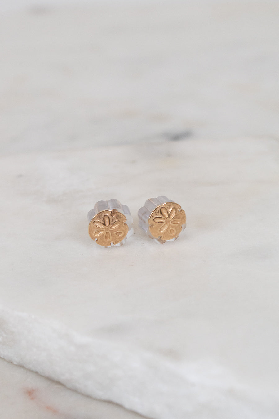 Gold stud earrings on a marble surface