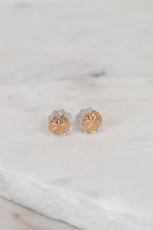 Gold stud earrings on a marble surface