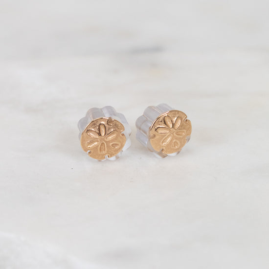 Gold round stud earrings on a light background