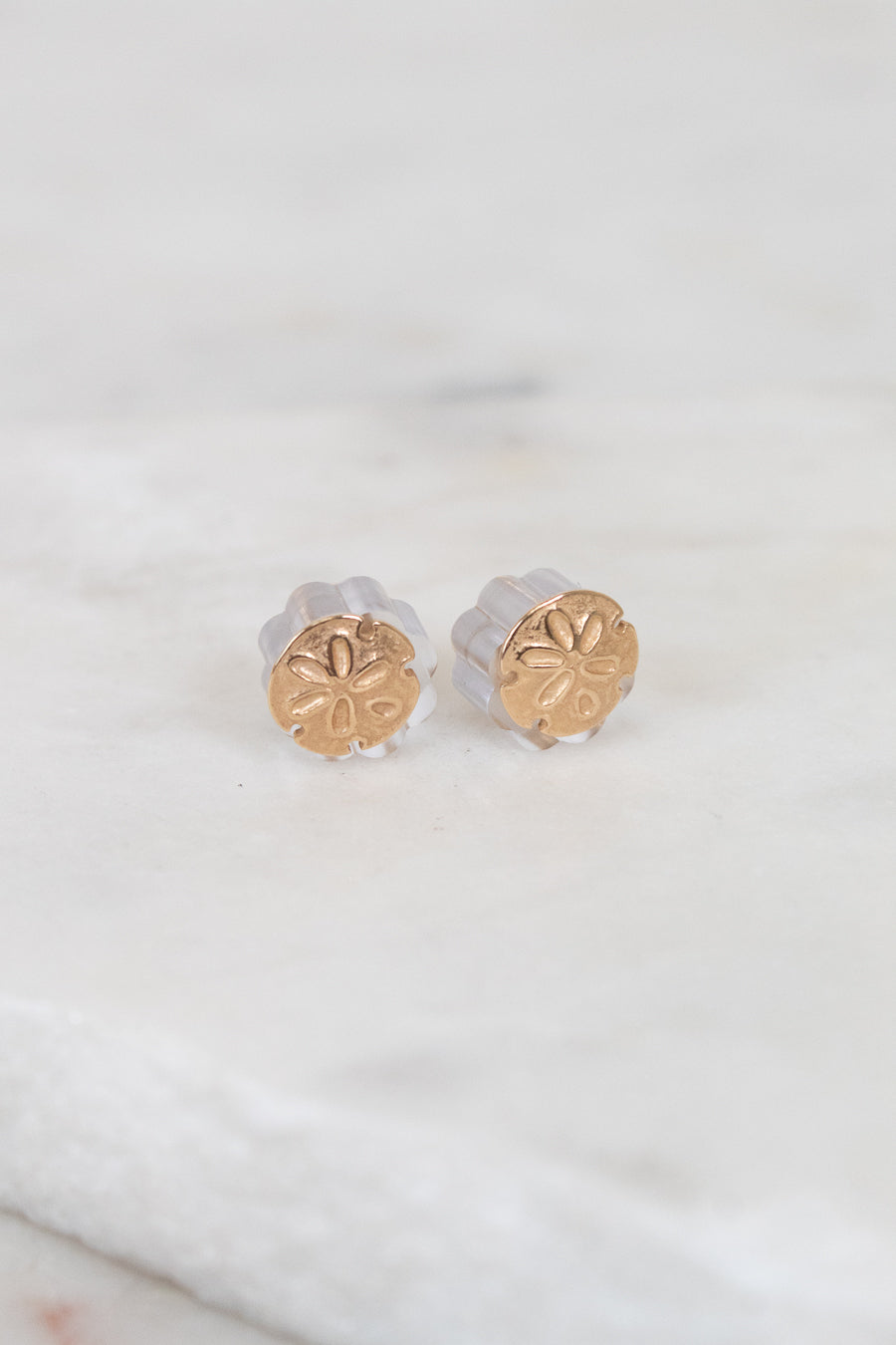 Gold round stud earrings on a light background