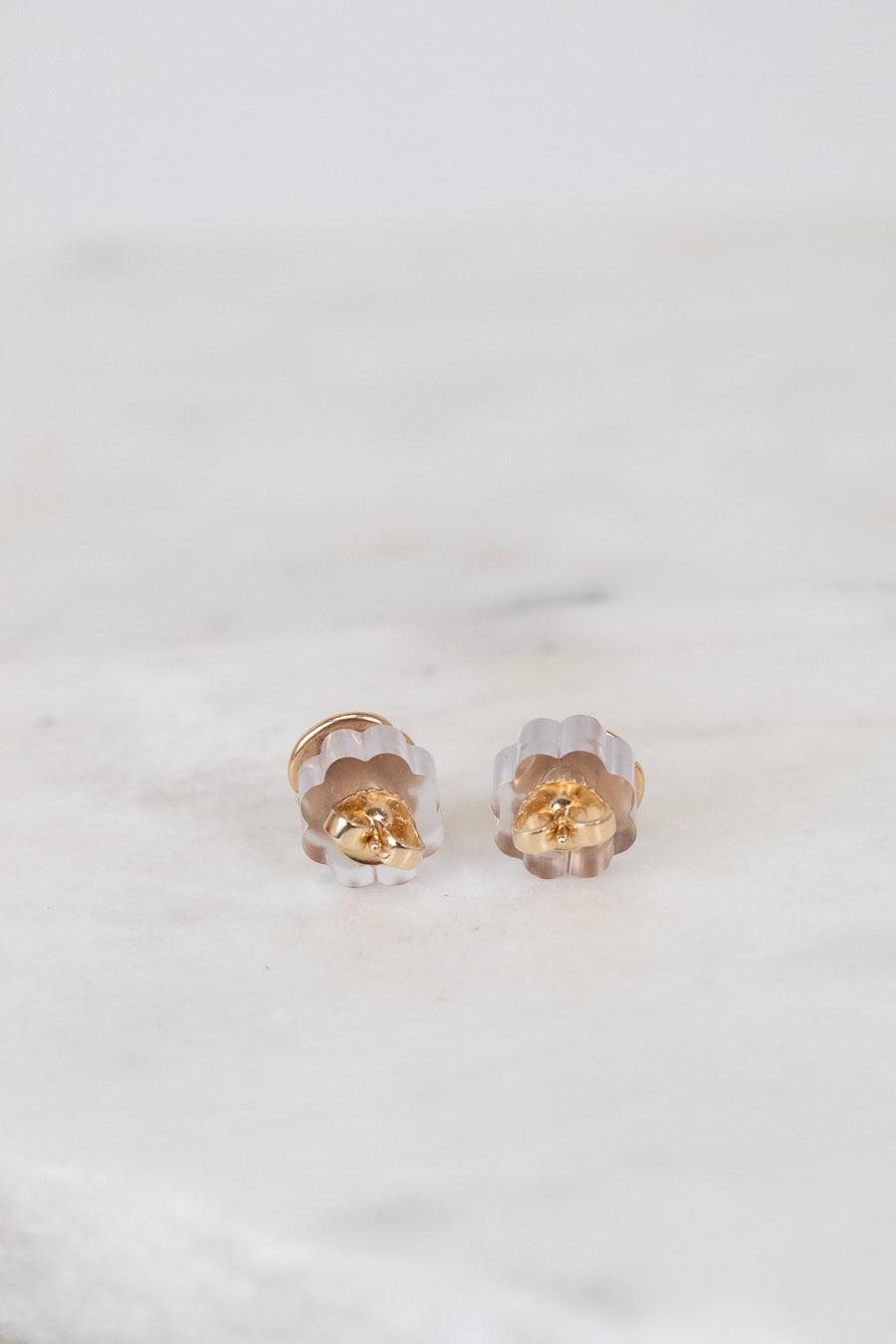 Pair of gold and clear sand dollar-shaped earrings on a white background
