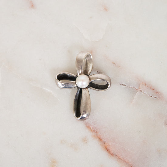 Silver cross pendant on a marble surface